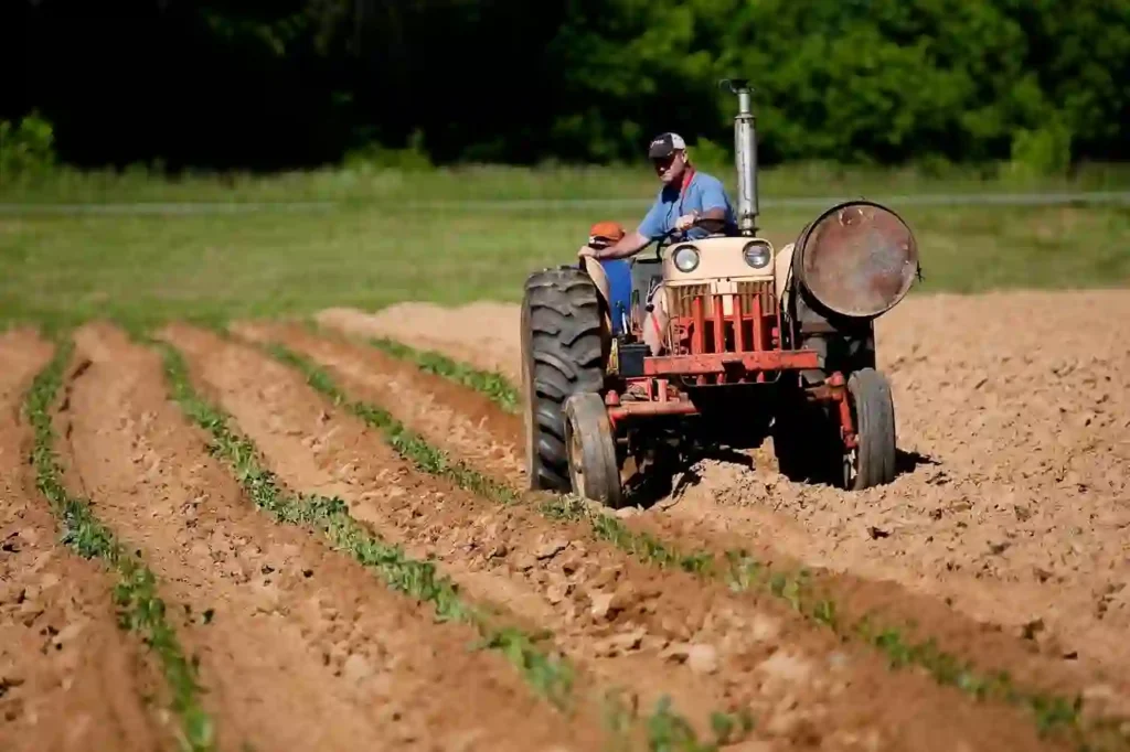 Agricultor conduciendo un tractor rojo en un campo arado, trabajando la tierra.