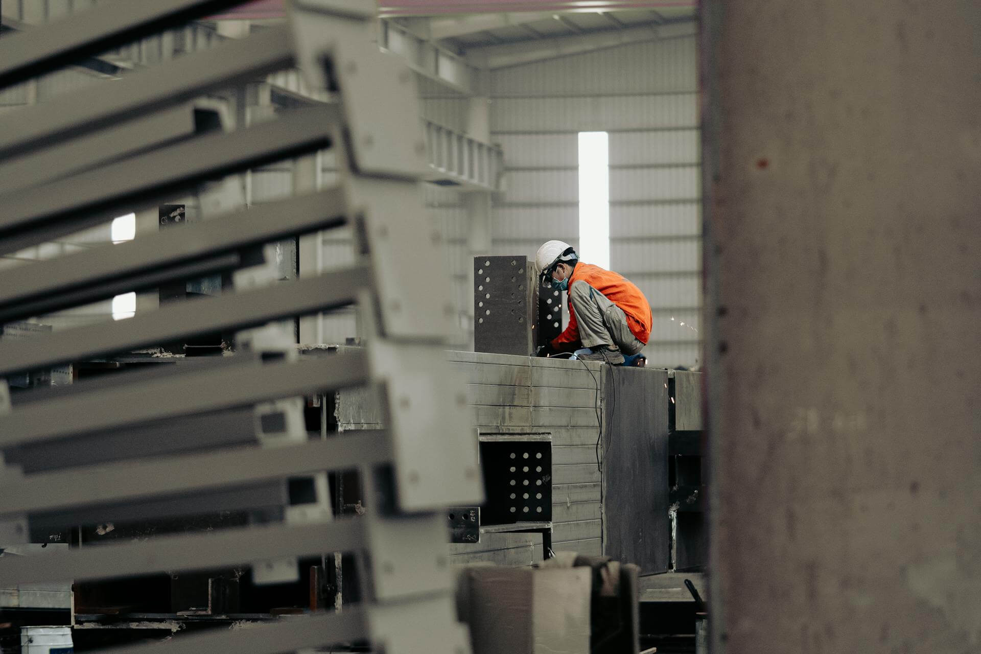 Trabajador en un entorno industrial, enfocado en ajustar o inspeccionar equipo mientras lleva puesto equipo de protección personal. La imagen captura la importancia de la seguridad en el lugar de trabajo, especialmente para aquellos que trabajan en condiciones aisladas o peligrosas.