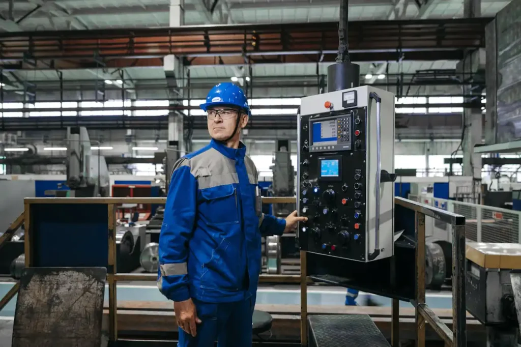 Operario con ropa de protección azul y casco de seguridad azul, utilizando un panel de control industrial en una planta de producción.